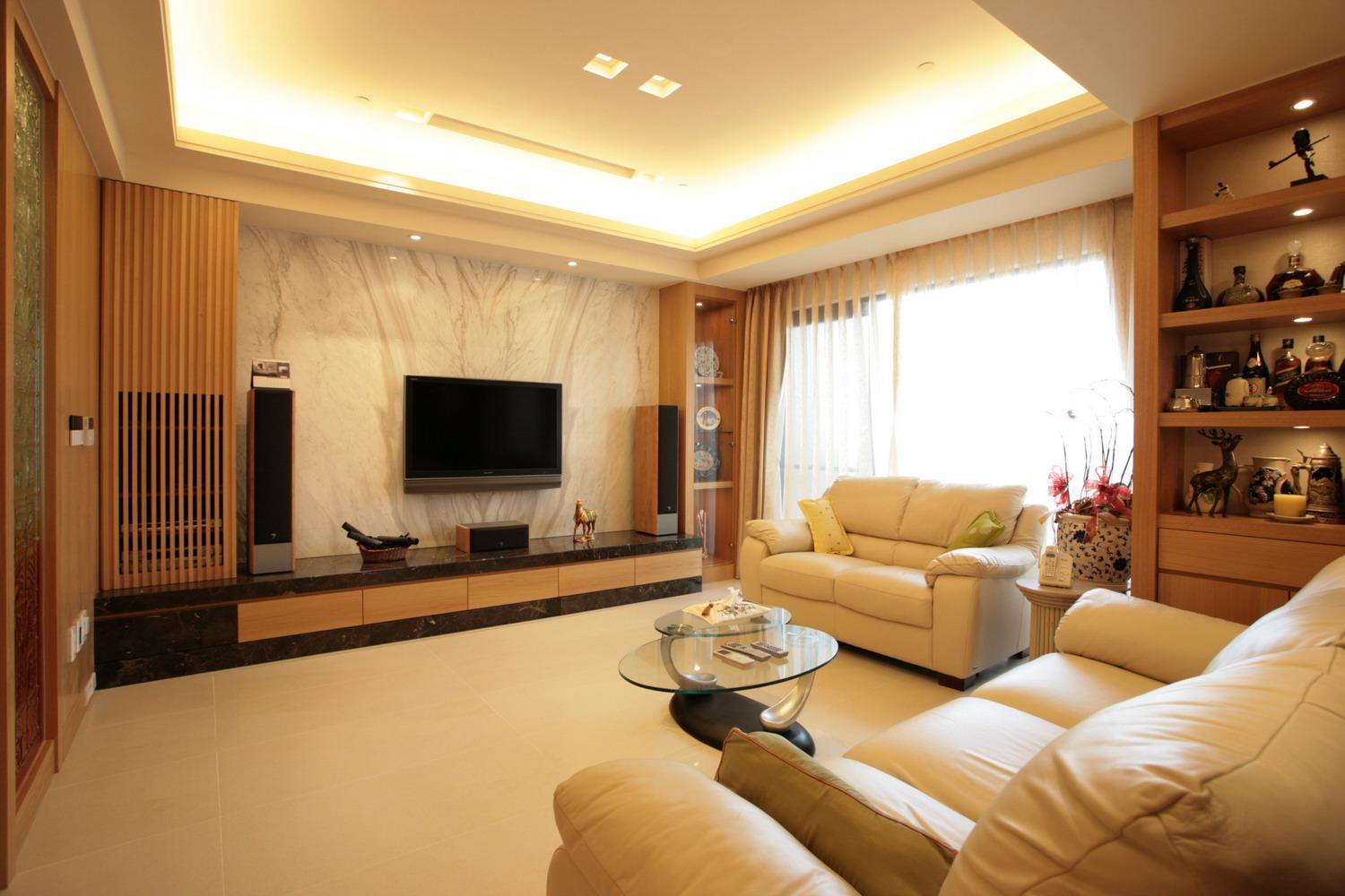 電視牆的設計以大理石材質展現出空間的大器，刻意不對稱的櫃體則各自賦不同的功能，右方玻璃櫃具有展示