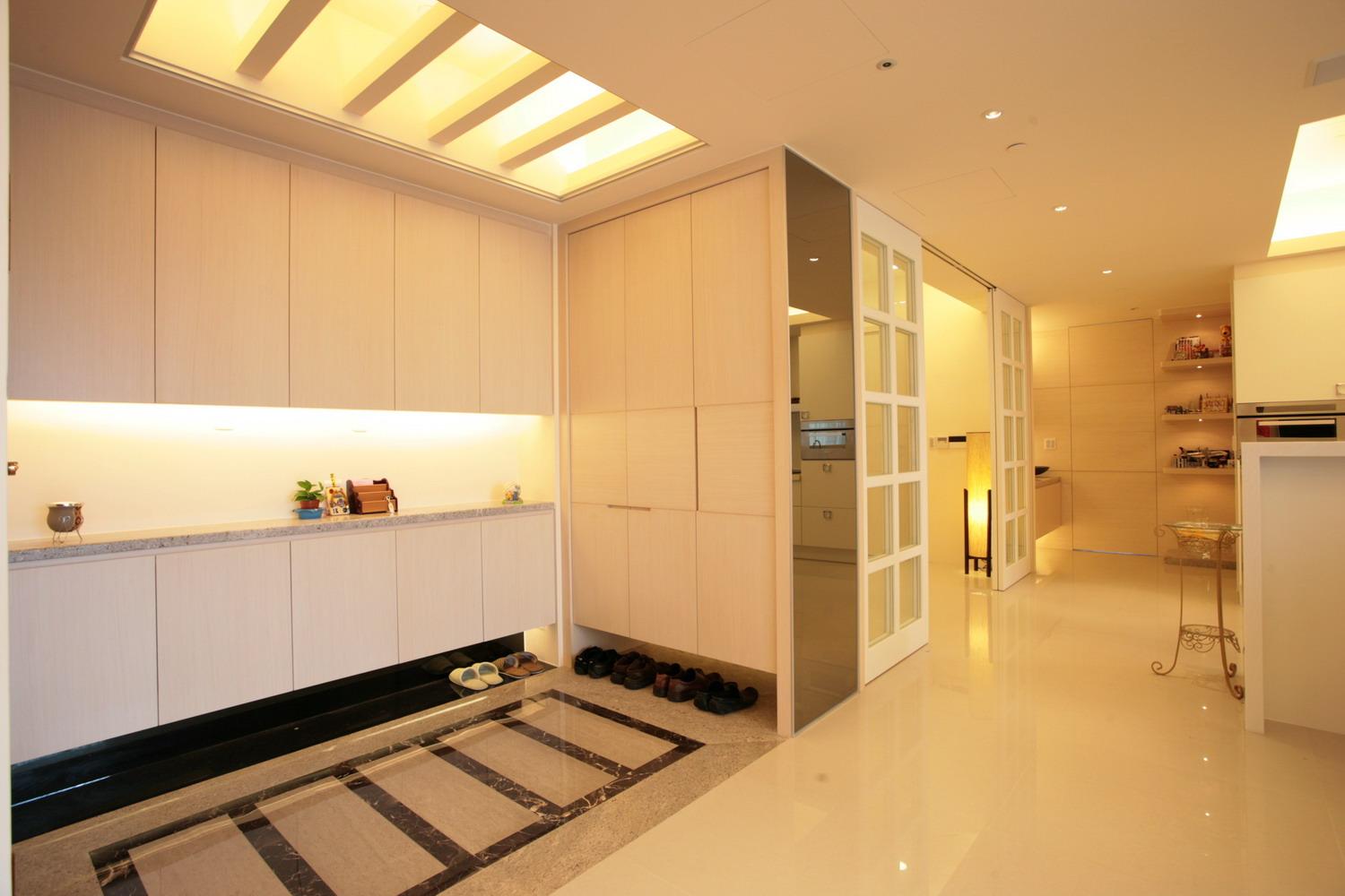 玄關的天花板與地坪採對稱式概念，地坪的大理石拼花與天花板的格柵燈槽相互呼應，兩側則是不落地